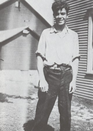 Erickson con 19 años. Posa de pie y de frente, ya totalmente recuperado de su ataque de polio, juento a cabañas de su pueblo en Nevada.